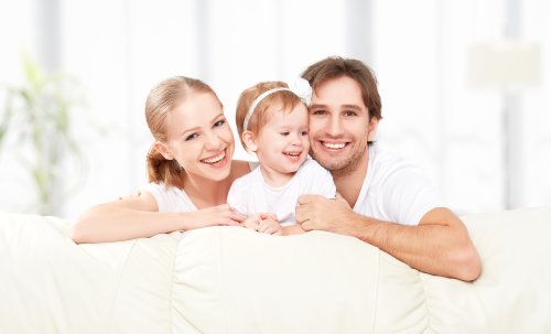 Ảnh gia đình hạnh phúc mẹ, cha, con gái vui cười trên ghế sofa