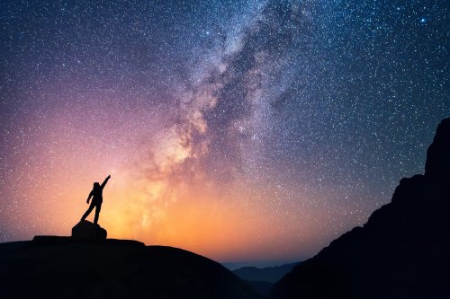 Ảnh chụp một người đang đứng cạnh dãi thiên hà chỉ vào ngôi sao sáng.