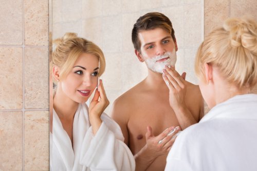 Ảnh chụp người đàn ông cạo râu và vợ làm sạch khuôn mặt trong gương ở phòng tắm