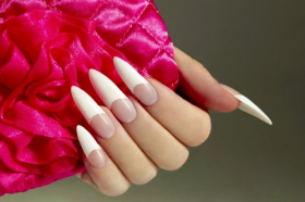 Ảnh chụp móng tay trắng của một phụ nữ với phụ kiện hoa hồng trên nền tối