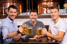 Ảnh chụp Ba người bạn vui vẻ cầm ly bia và mỉm cười với camera