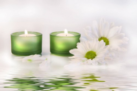 Hình ảnh hai ngọn nến màu xanh và hoa cúc phản chiếu trên mặt nước