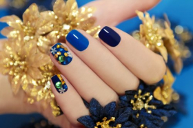 Ảnh móng tay của phụ nữ được bao phủ bởi sơn mài màu xanh với đá hoa râm và hoa trong tay